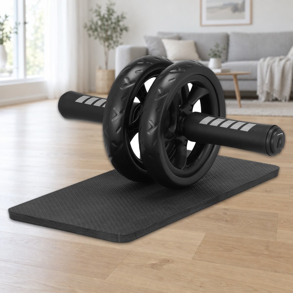 Ab wheel met twee wielen van 15 cm en foamgrepen, staand op de zwarte kniemat op een lichte parketvloer