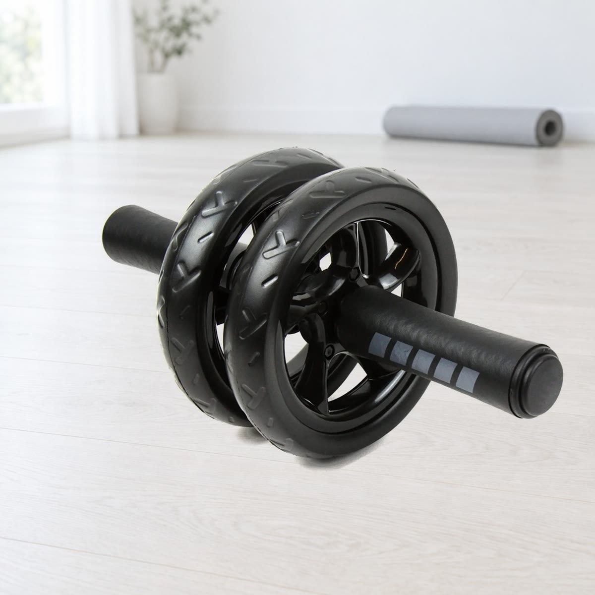 Ab wheel met twee zwarte wielen met profiel en foamgrepen met grijze strepen, op een lichte houten vloer