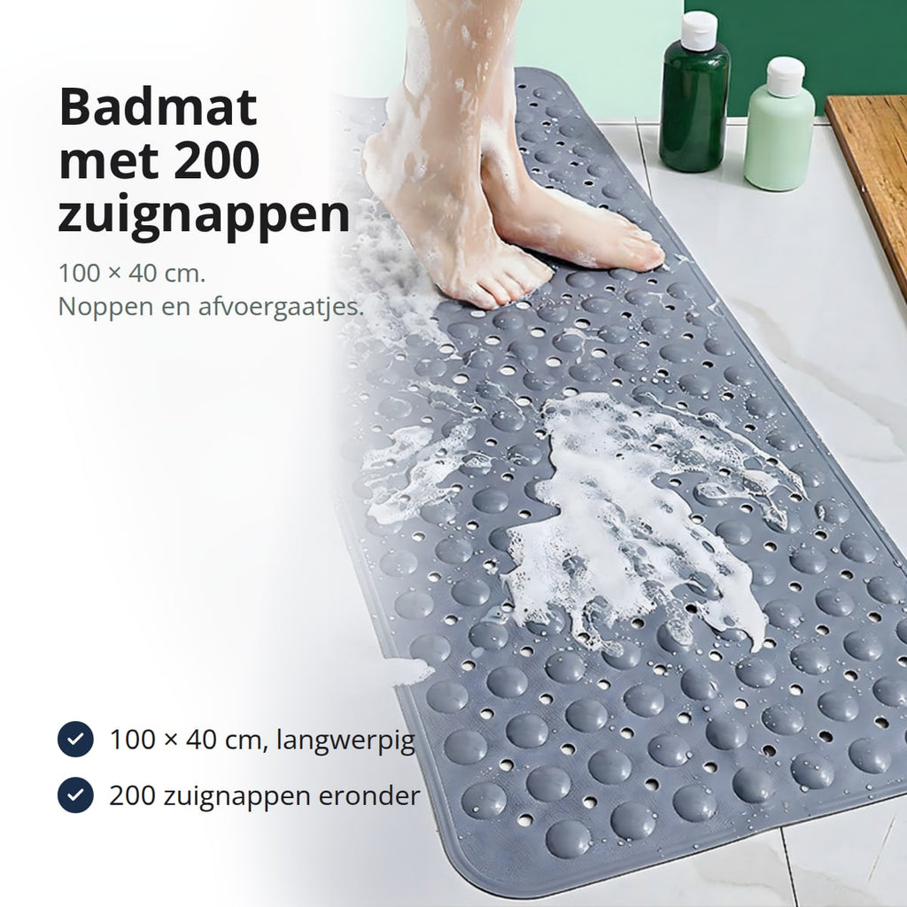 Antislip badmat met noppen en afvoergaatjes in een bad, met een voet op de mat
