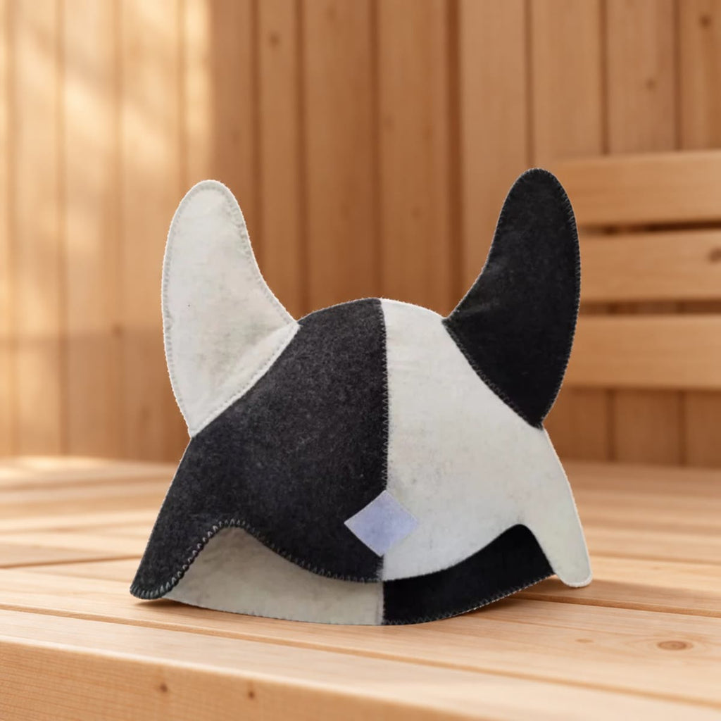 De saunamuts met twee hoorns op een bank in een sauna met houten wanden, van voren gezien met het labeltje zichtbaar