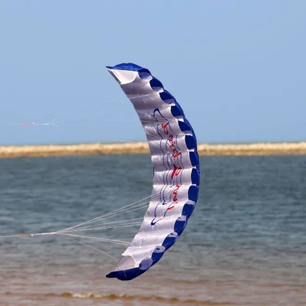 De stuntvlieger in de blauwe uitvoering boven de zee, met licht doek en een blauwe voorrand