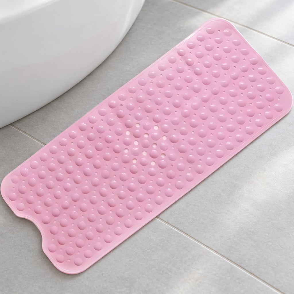 Roze badmat met noppen en een uitsparing aan het uiteinde, op een lichte badkamervloer