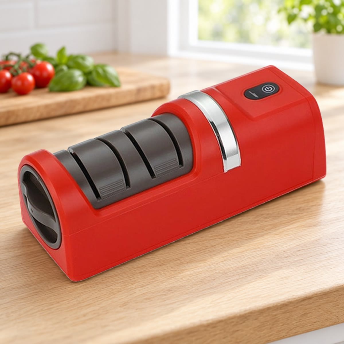 Rode elektrische messenslijper op een eiken aanrecht, met tomaten en basilicum op de achtergrond