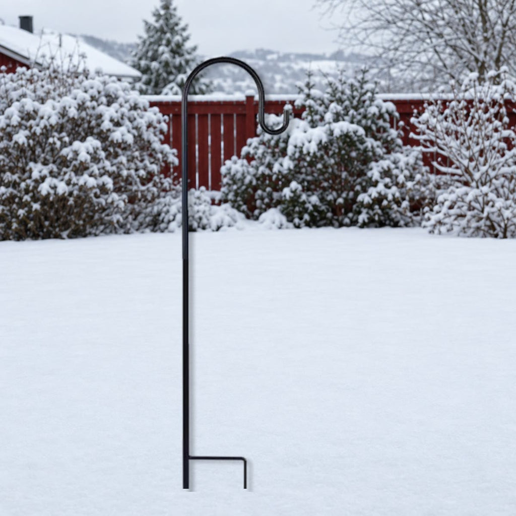 Zwarte metalen haak met voetbeugel, in de sneeuw gestoken in een tuin in de winter