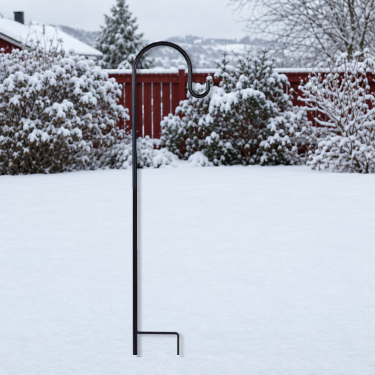 Zwarte metalen haak met voetbeugel, in de sneeuw gestoken in een tuin in de winter