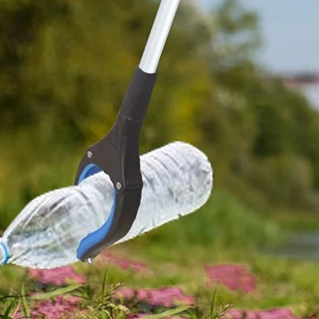 De grijpstok raapt buiten een lege plastic fles op uit het gras