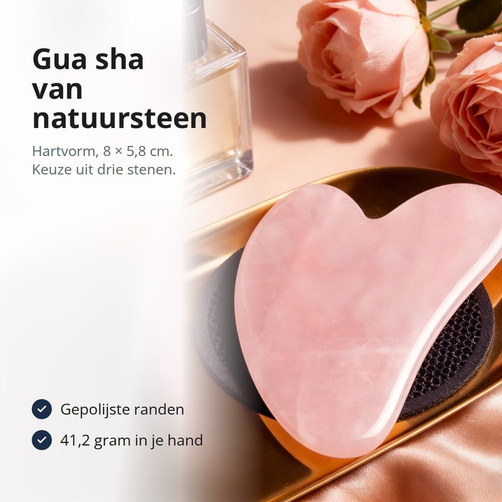 Hartvormige gua sha van rozenkwarts op een gouden schaaltje naast rozen