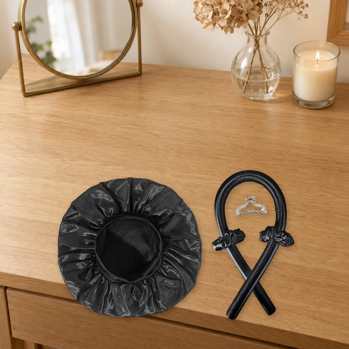 Heatless curls set in zwart: krulstaaf, satijnen muts, scrunchies en haarklem op een kaptafel