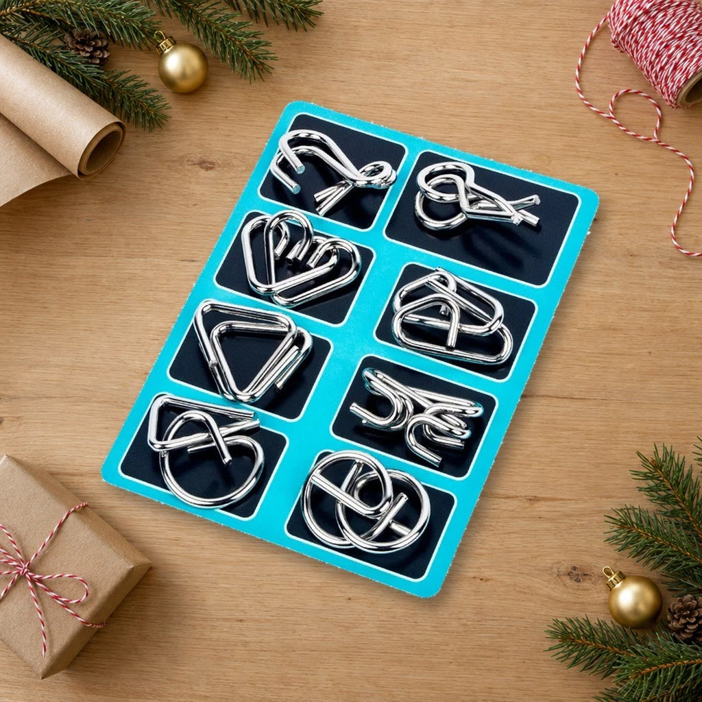 Breinbrekers van metaal op een blauw bord naast kerstpapier, dennentakken en een klein cadeautje op een houten tafel
