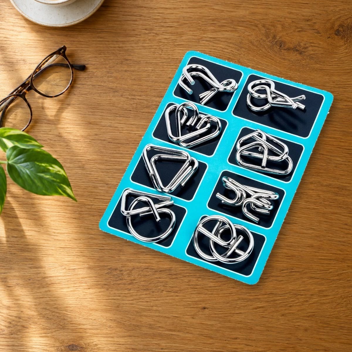 Bord met acht metalen puzzels op een salontafel naast een kop koffie en een bril