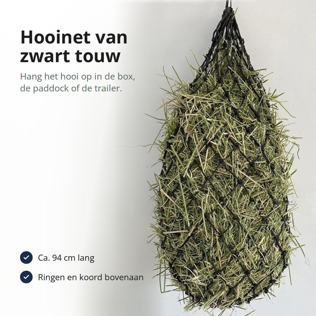 Zwart hooinet van geknoopt touw gevuld met hooi, met de tekst: hooinet van zwart touw, hang het hooi op in de box, de paddock of de trailer; ca. 94 cm lang; ringen en koord bovenaan