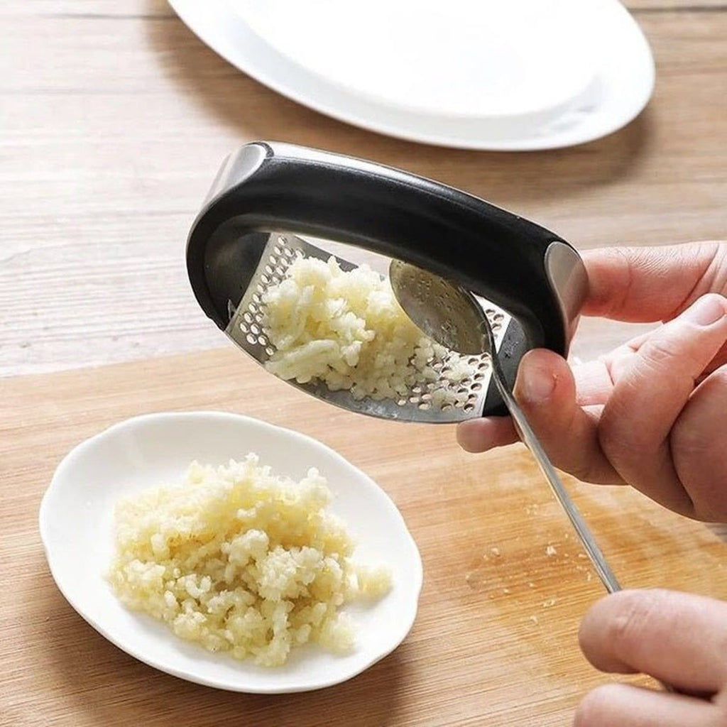 Geperste knoflook wordt met een lepel van de stalen plaat geschraapt boven een bord
