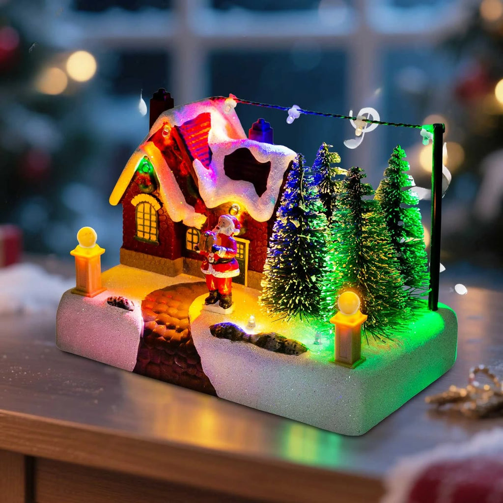 Het kerstdorp brandend op een tafel voor een raam, de dennenbomen lichten groen en blauw op