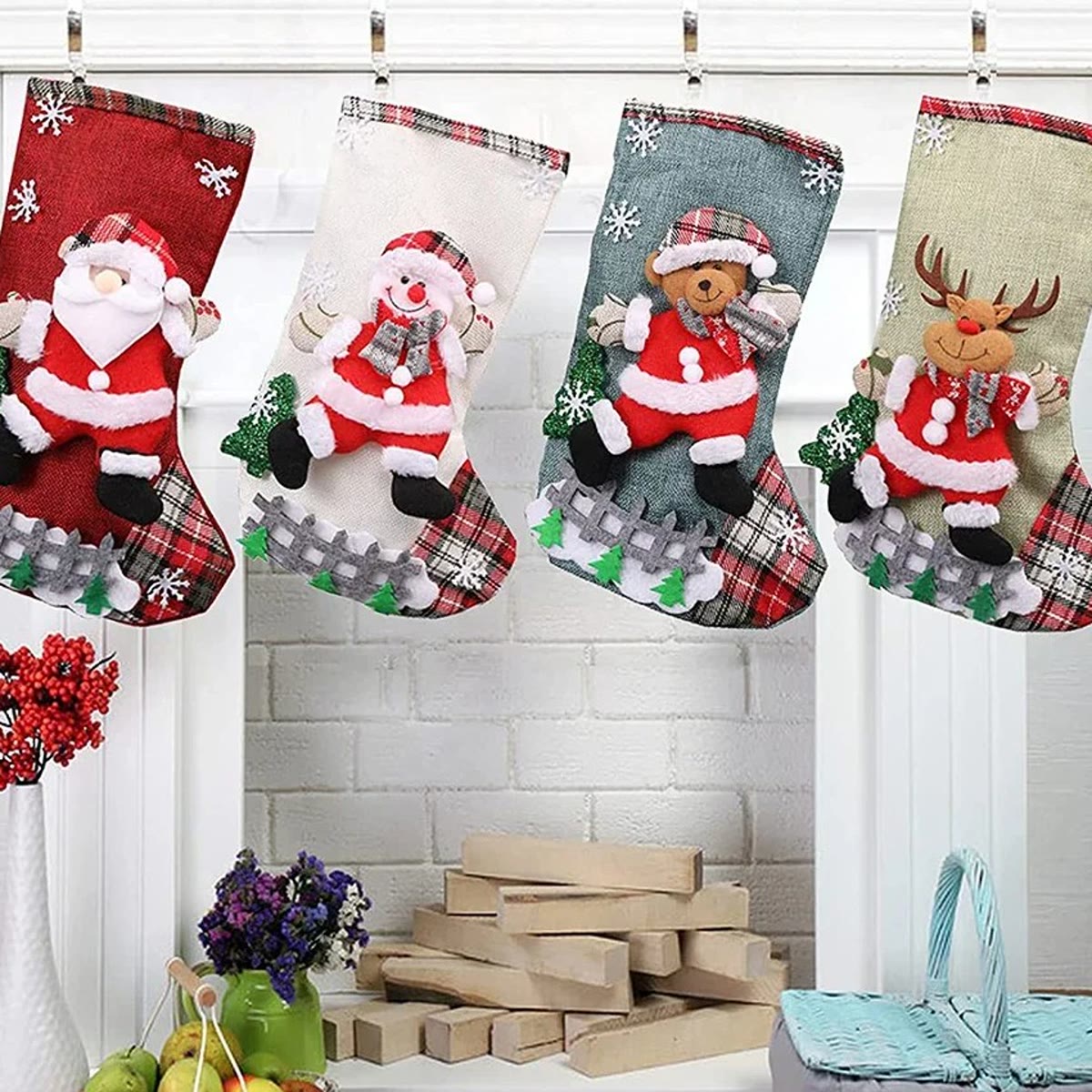 Vier kerstsokken aan haakjes aan een witte bakstenen schouw