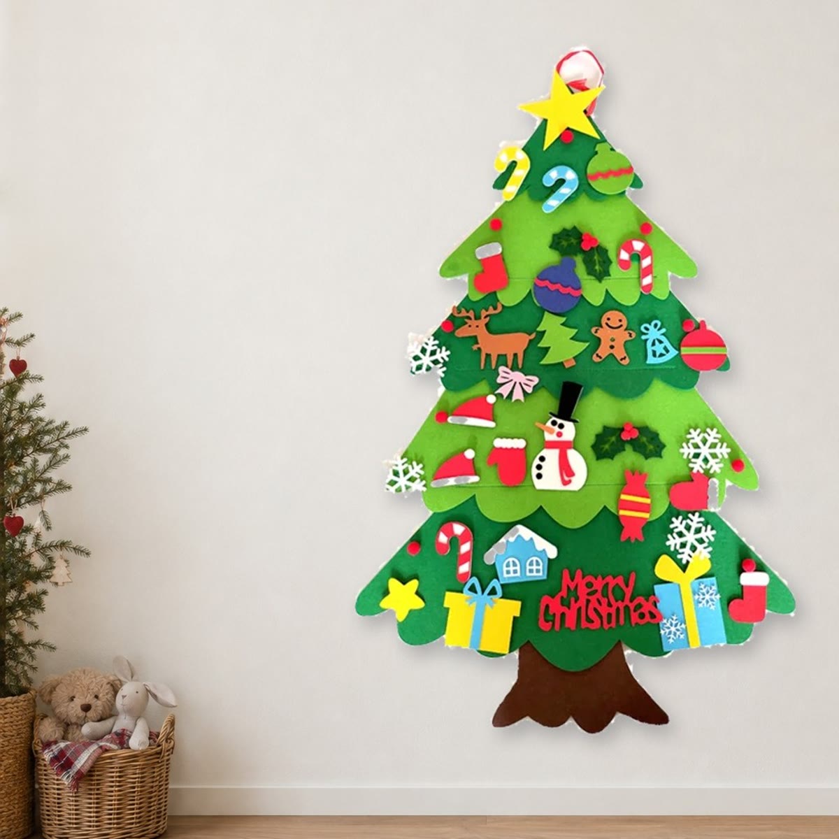 Vilten kerstboom met 32 versieringen aan een lichte muur in een kinderkamer