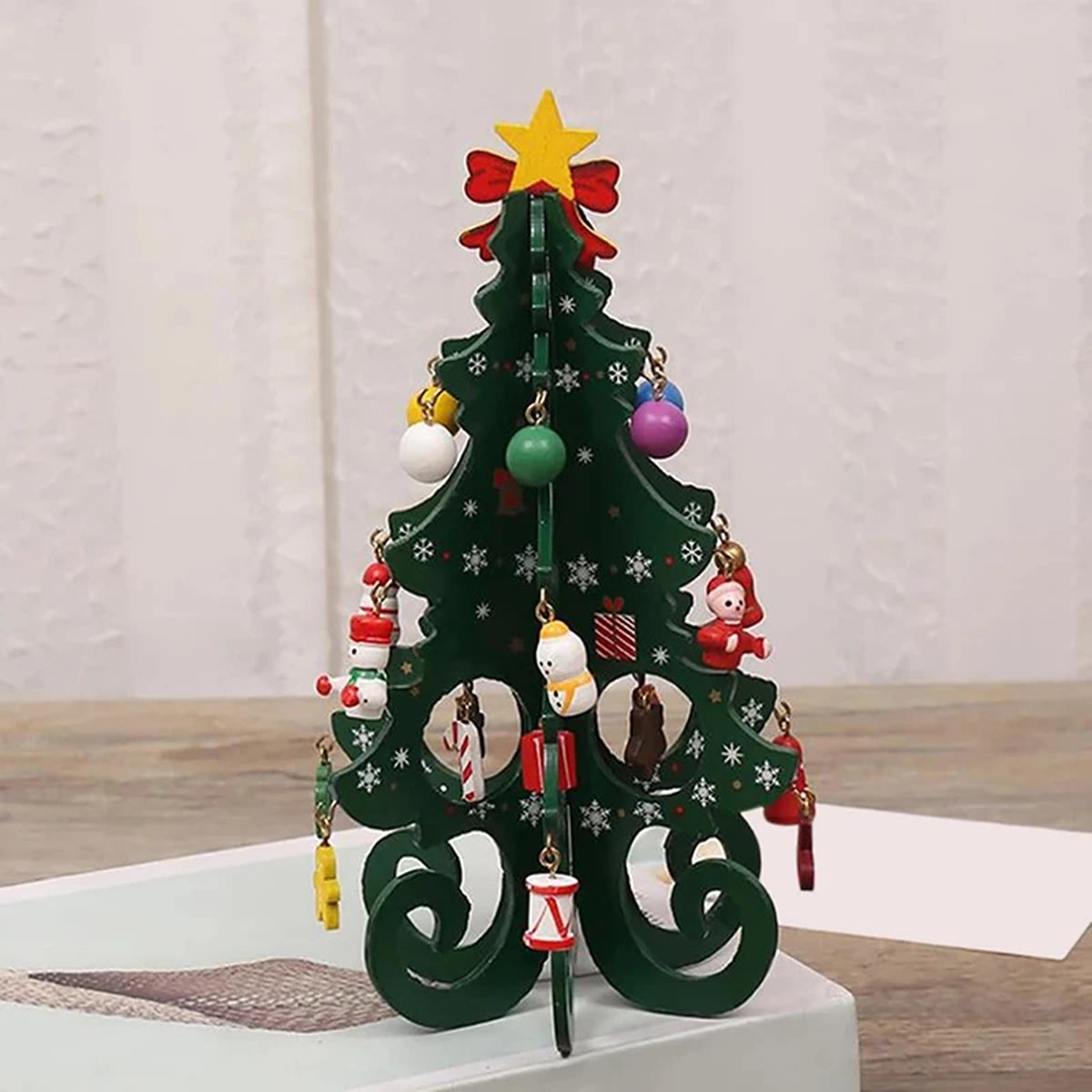 Groene houten kerstboom met sneeuwvlokkenprint en kleine figuurtjes en balletjes van hout