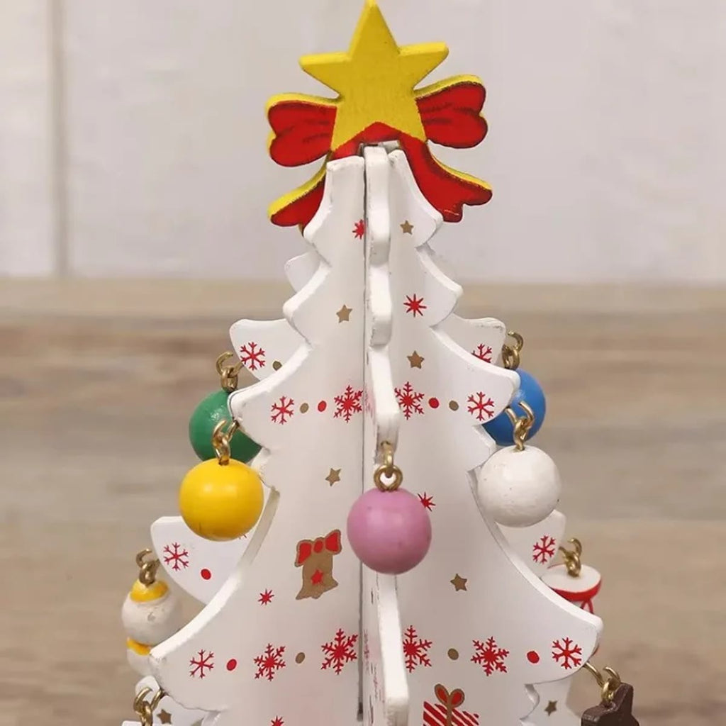 De top van een witte houten kerstboom met gele ster, rode strik en houten balletjes