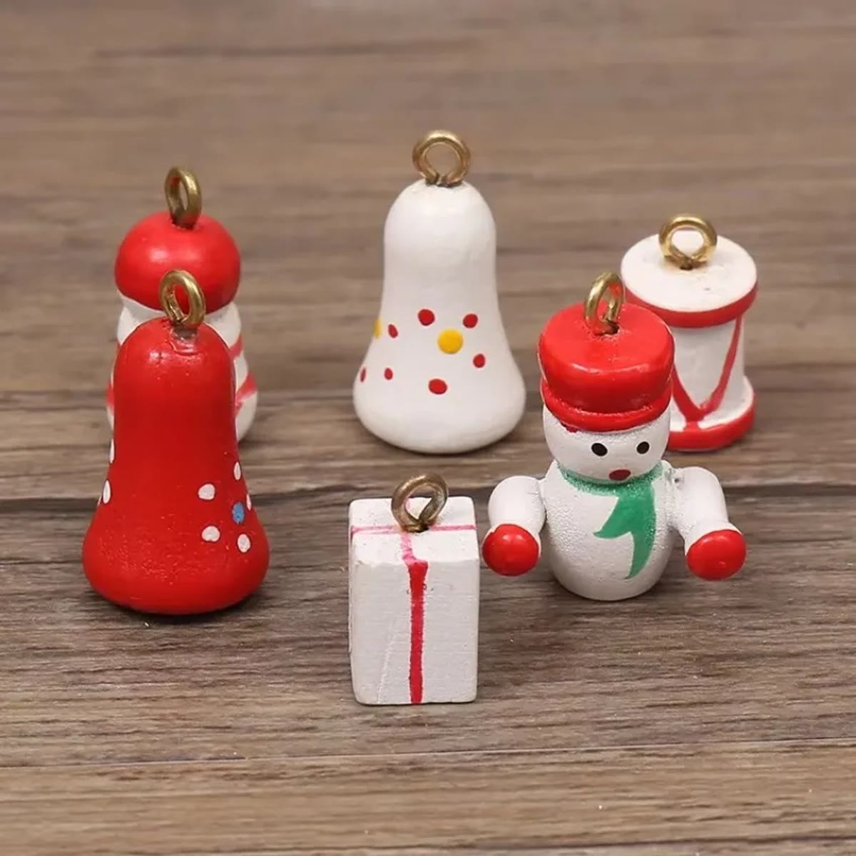 Close-up van kleine houten versieringen met haakje: belletjes, sneeuwpop, cadeautje en trommel