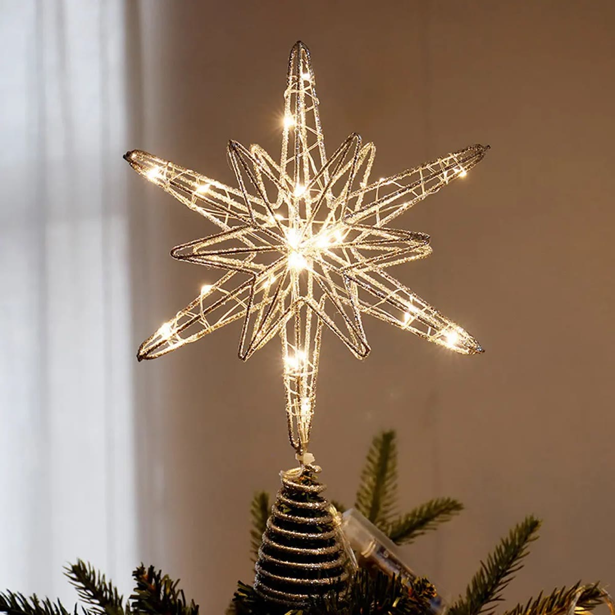 Zilveren kerstboomster brandend in de top van een kerstboom, de spiraalvoet over de toptak geschoven