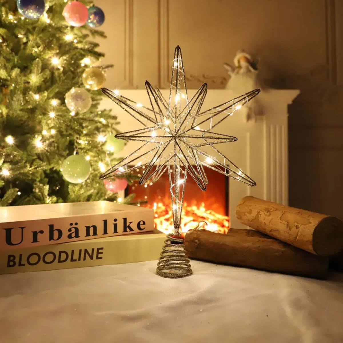 Zilveren kerstboomster brandend voor een open haard met een kerstboom op de achtergrond