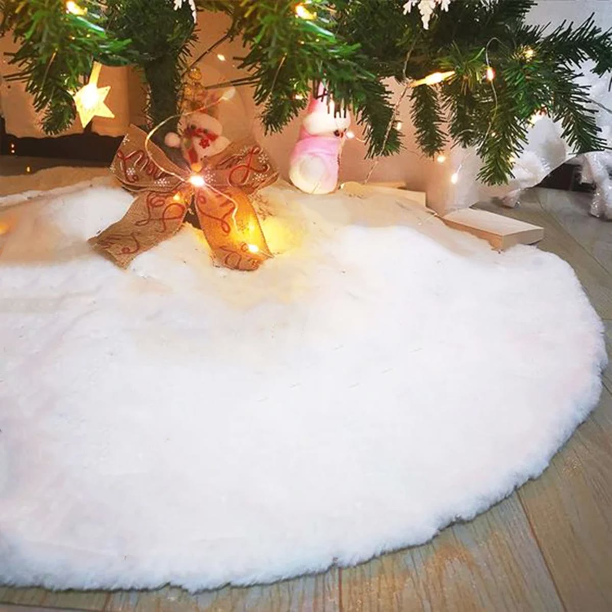 Close-up van de lange, witte pluche van de kerstboomrok onder een kerstboom met lichtsnoer