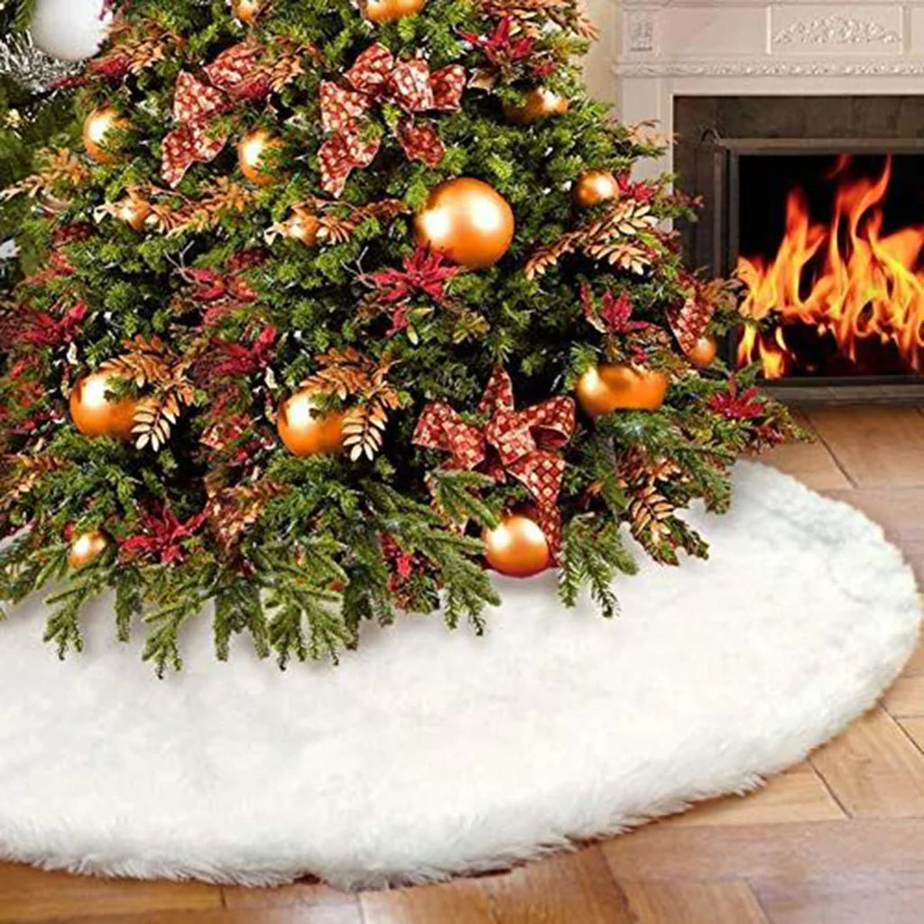 Witte kerstboomrok van pluche rond de voet van een kerstboom met gouden kerstballen