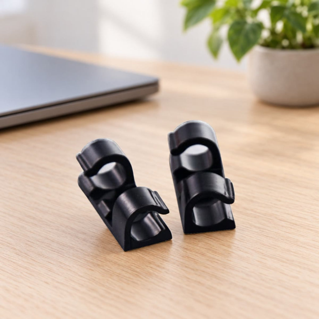 Zwarte kabelclips op een eikenhouten bureau naast een laptop
