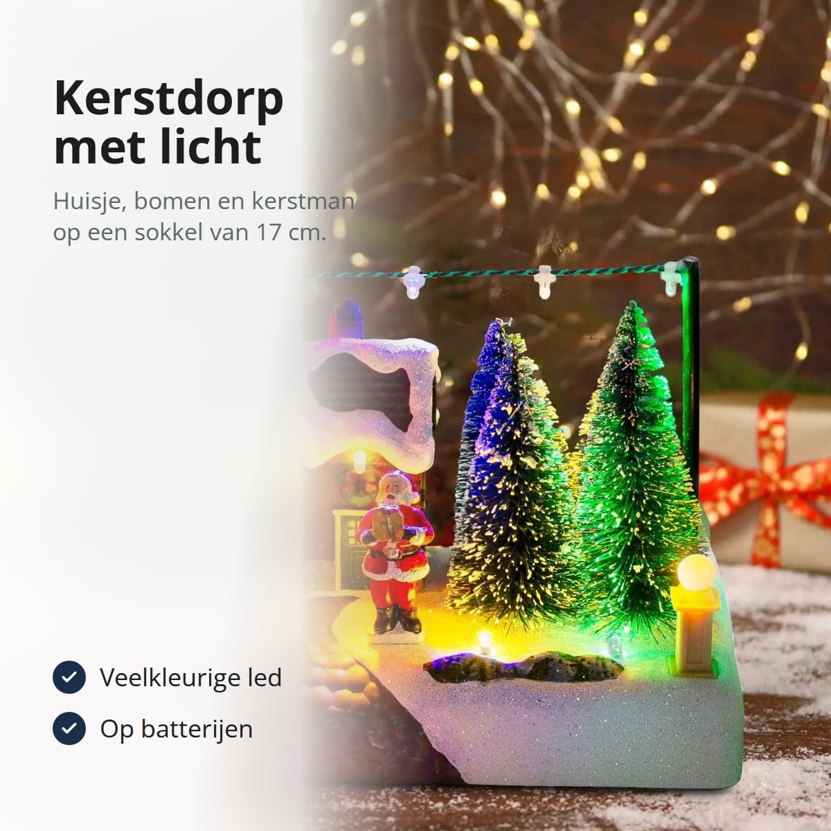 Kerstdorp met verlichting op een besneeuwde sokkel, met tekst: veelkleurige led, op batterijen zonder snoer