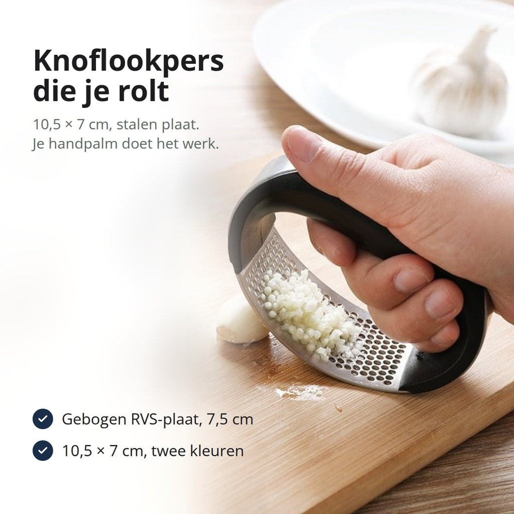 Hand rolt de knoflookpers over een teen knoflook op een snijplank
