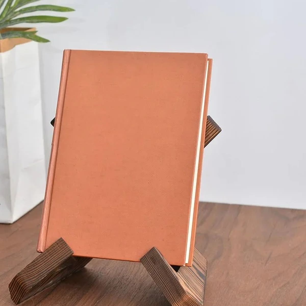 Gesloten boek met oranje kaft op een houten kookboekstandaard op een houten tafel