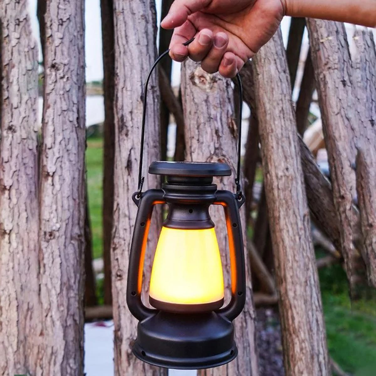 De LED lantaarn hangend aan een tak, met warm licht in de kap