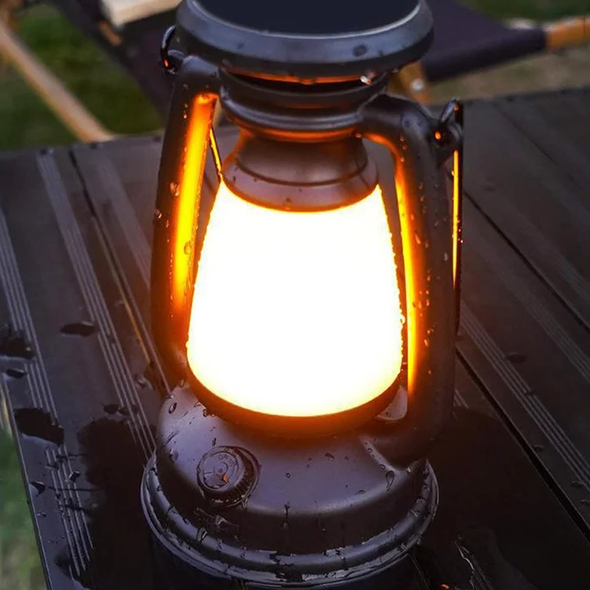De lantaarn 's avonds op een tafel buiten, met geel licht als van een kaars