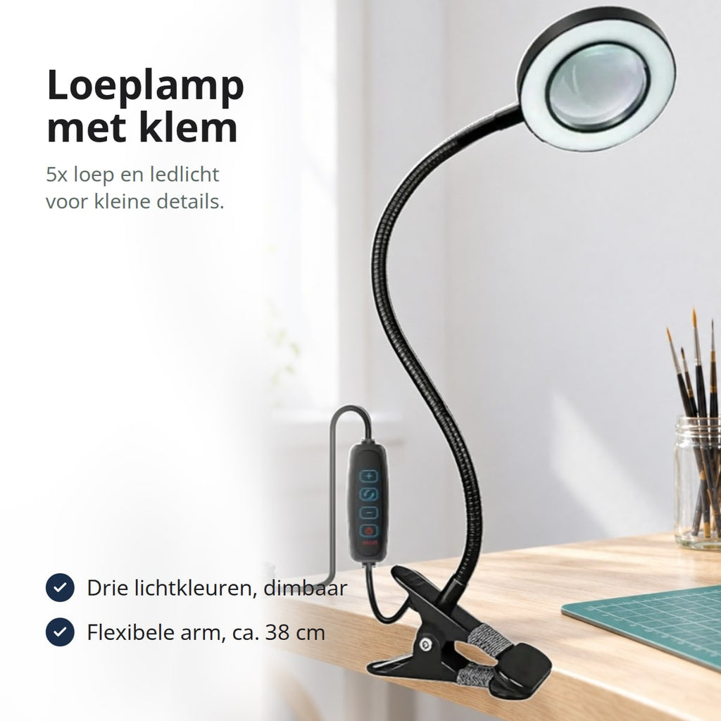 Zwarte loeplamp met klem, flexibele arm en brandende ledring op een hobbytafel met penselen en een figuur