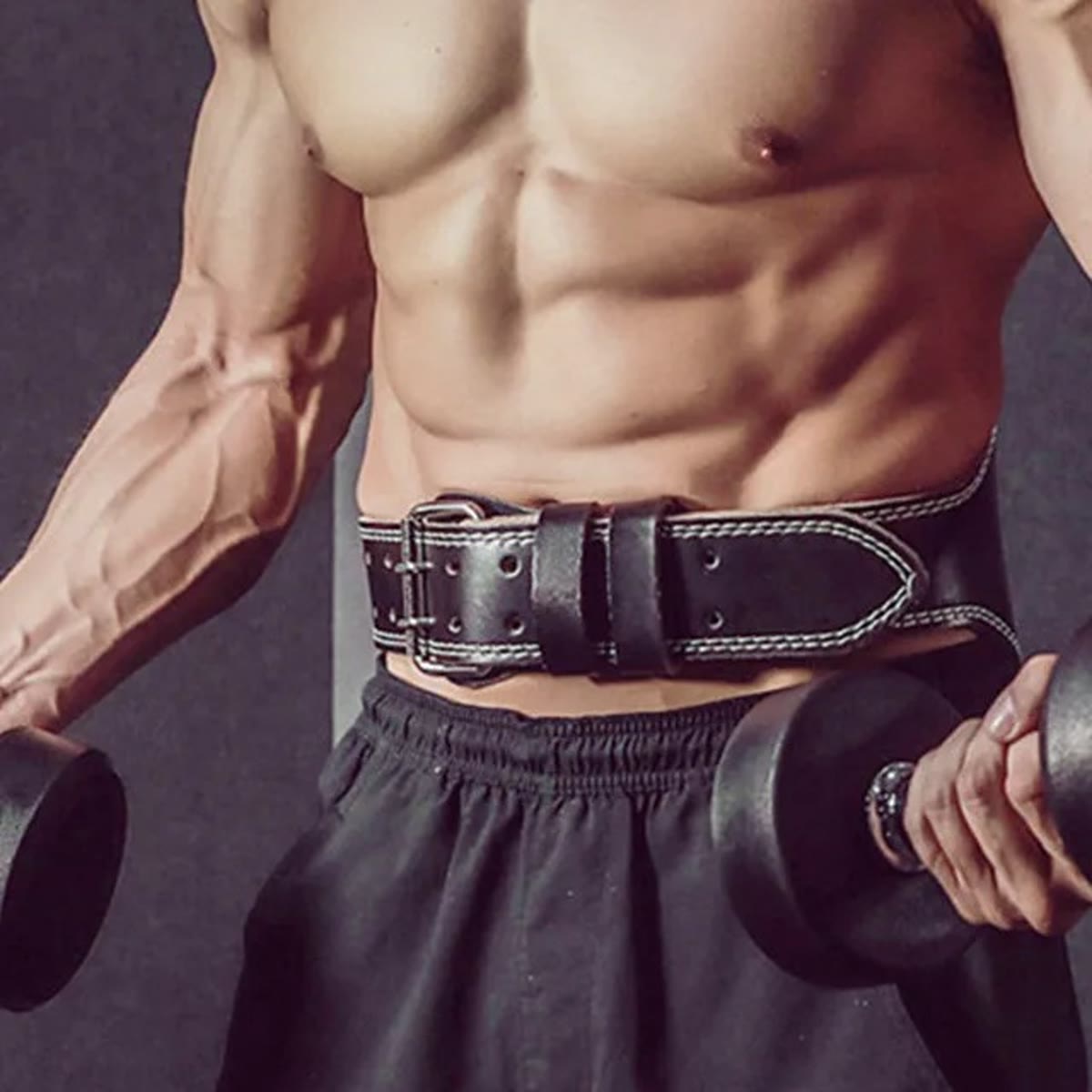 Man met de zwarte lifting belt strak om zijn middel en een dumbbell in elke hand