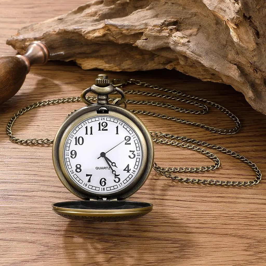 Open zakhorloge met witte wijzerplaat en Arabische cijfers op een houten tafel, met ketting en drijfhout erachter