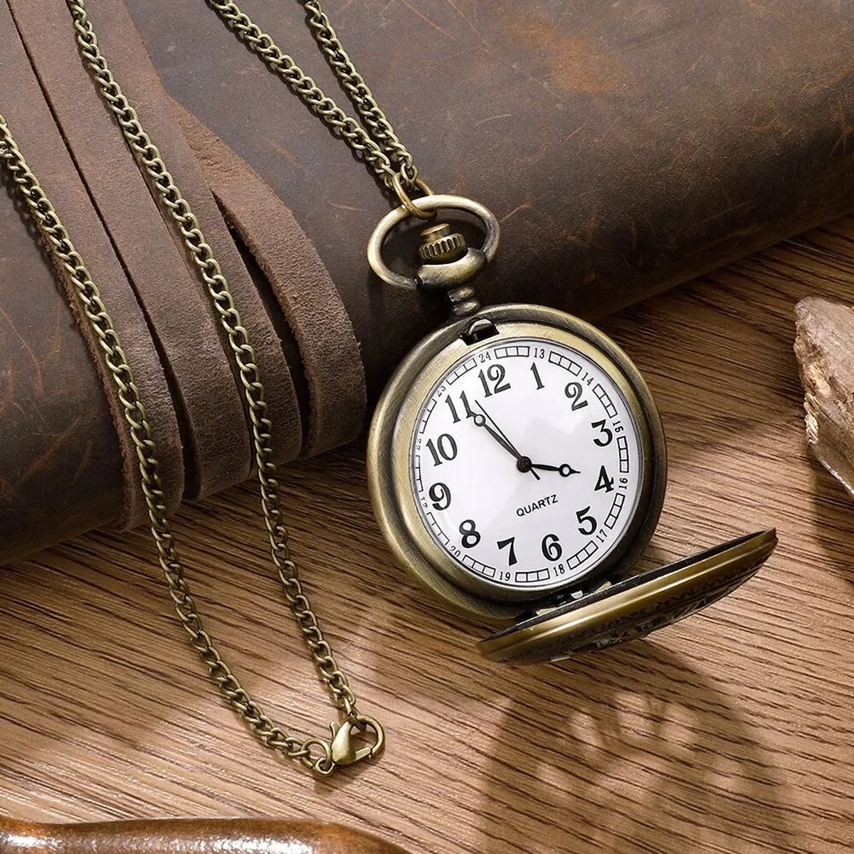 Open zakhorloge met ketting voor een rol leer op een houten tafel