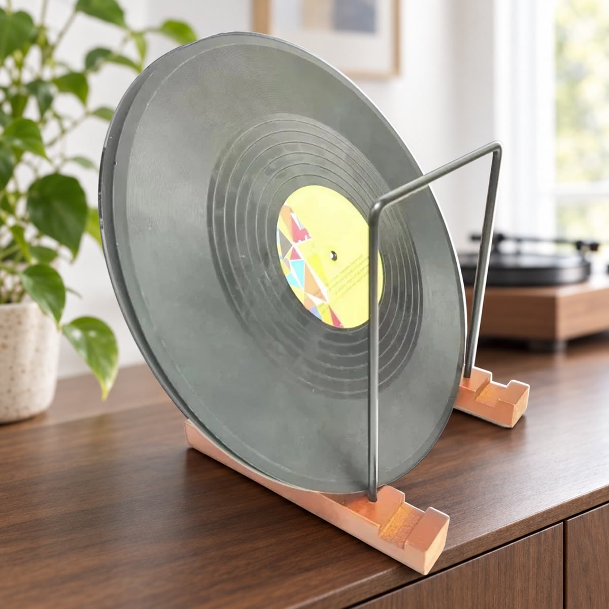 Vinylplaat rechtop in een LP standaard met houten voetjes en zwarte metalen frames op een notenhouten dressoir