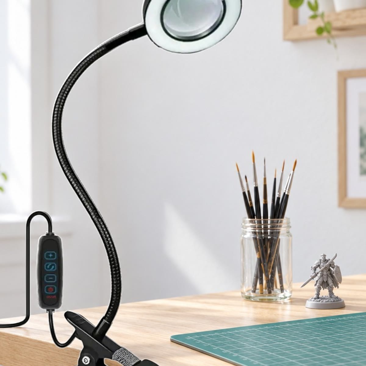 Loeplamp met klem aan een lichte hobbytafel met penselen in een glas, een miniatuurfiguur en een snijmat