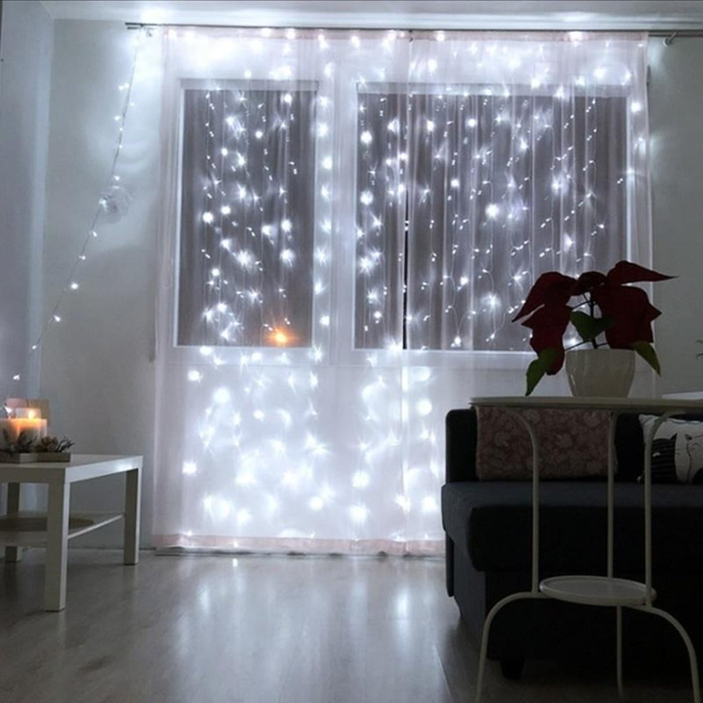 Wit lichtgordijn voor een raam in een woonkamer, met een kerstster in de vensterbank