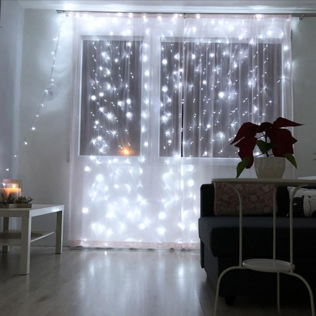 Wit lichtgordijn voor een raam in een woonkamer, met een kerstster in de vensterbank