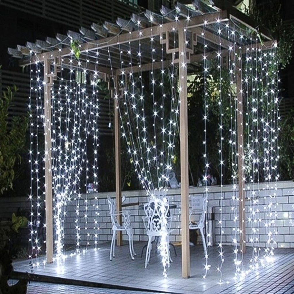 Lichtgordijn opgehangen in een witte pergola op een terras, 's avonds