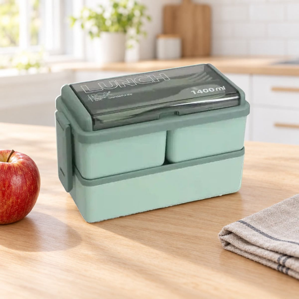 Groene bento box met twee lagen op een keukentafel naast een theedoek