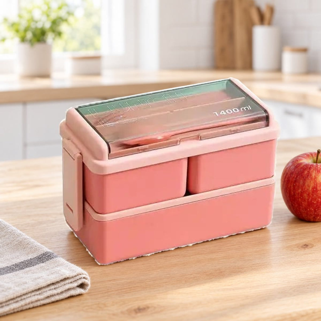 Roze bento box met twee lagen op een keukentafel naast een appel