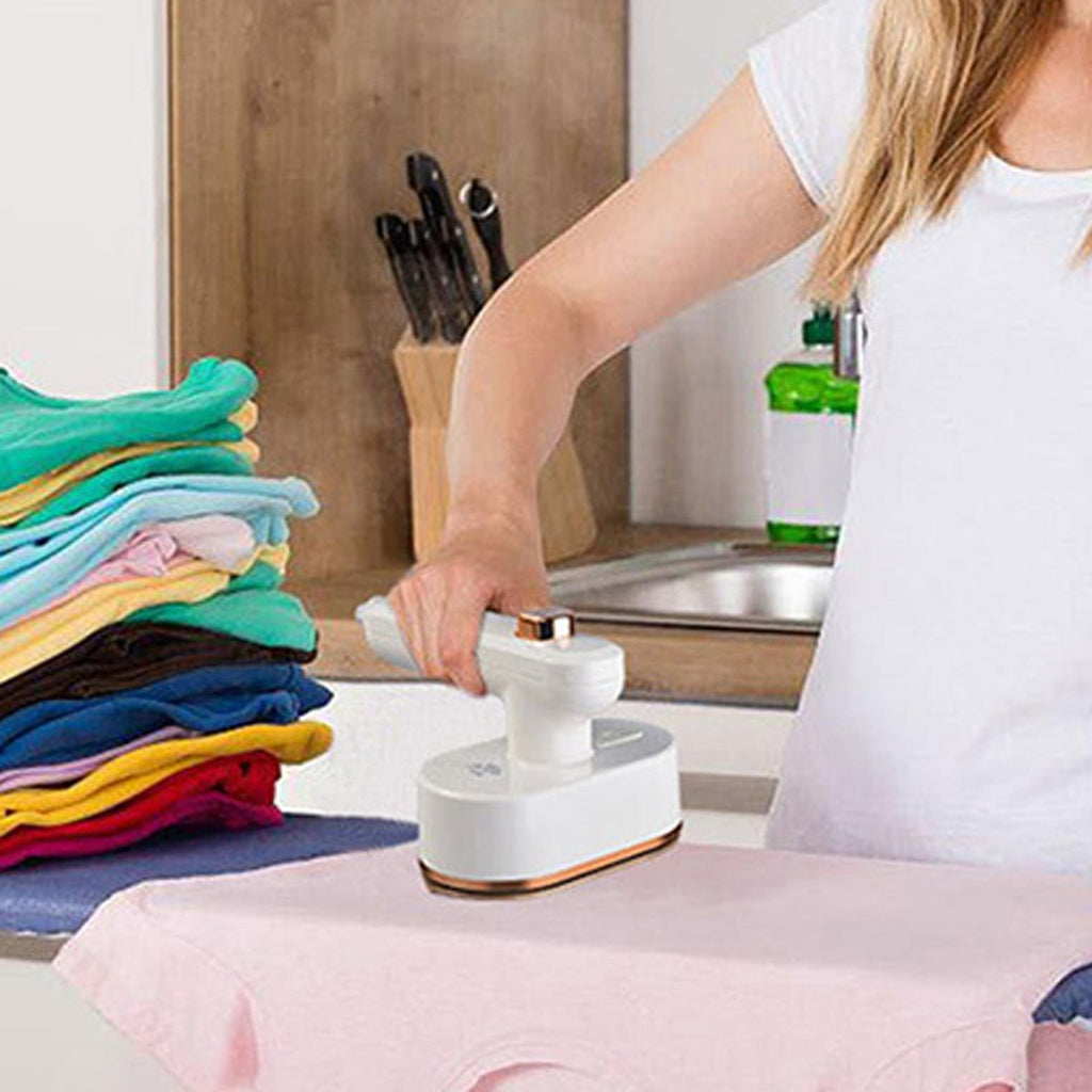 Vrouw die een roze T-shirt strijkt met het witte mini strijkijzer op het aanrecht