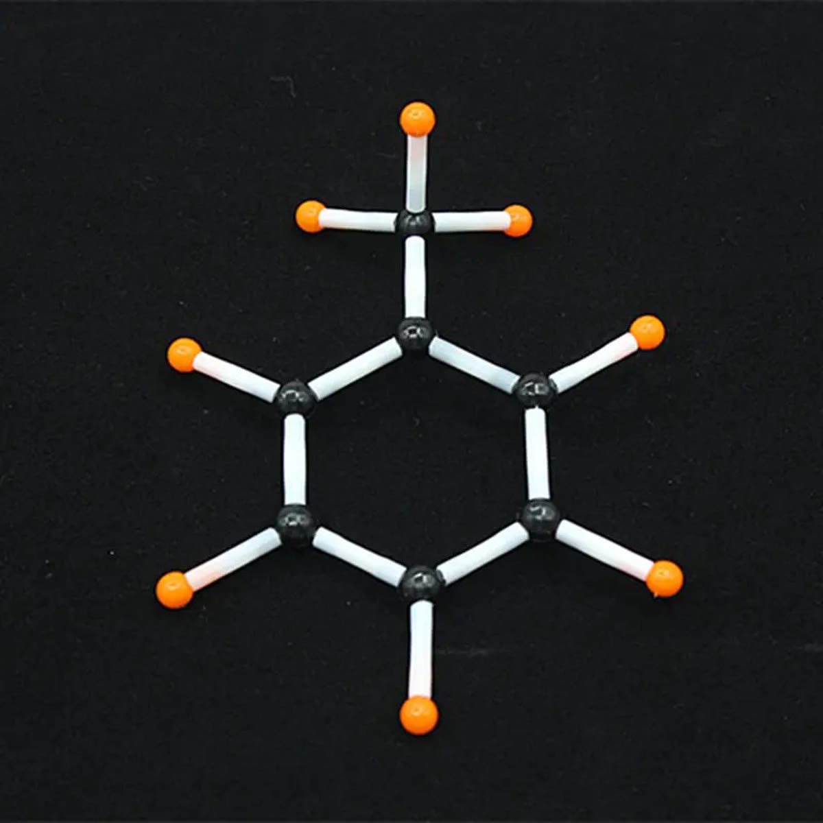 Zesring van zwarte koolstofatomen met oranje waterstofatomen en witte plastic buisjes, gebouwd met de molecuulbouwdoos