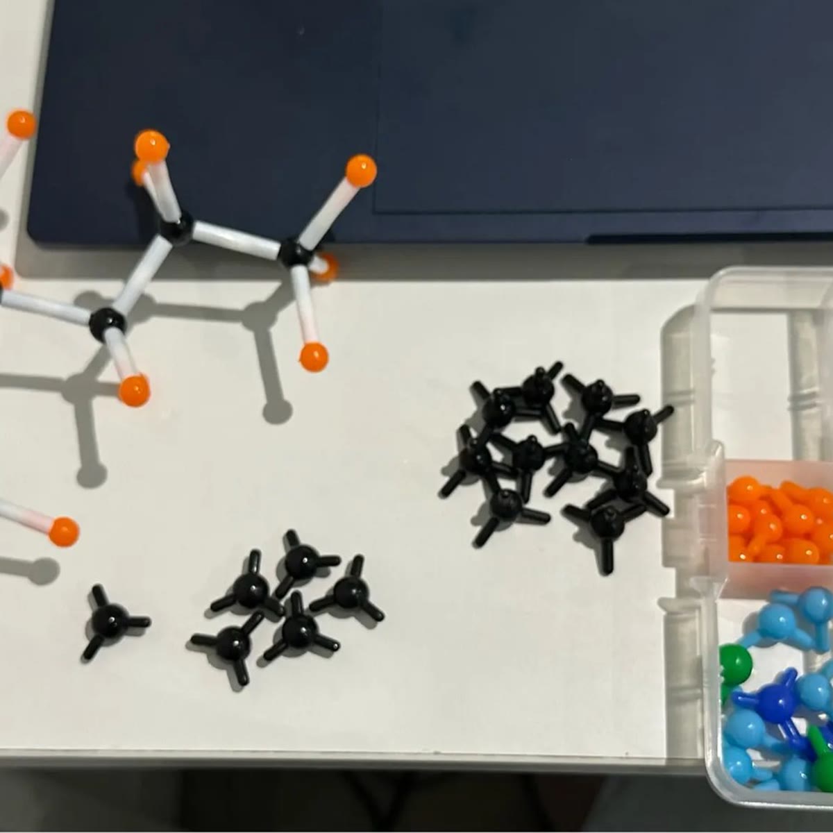 Kant-en-klaar model van een koper: een koolstofskelet met waterstofatomen op een wit bureau, naast de doos met onderdelen