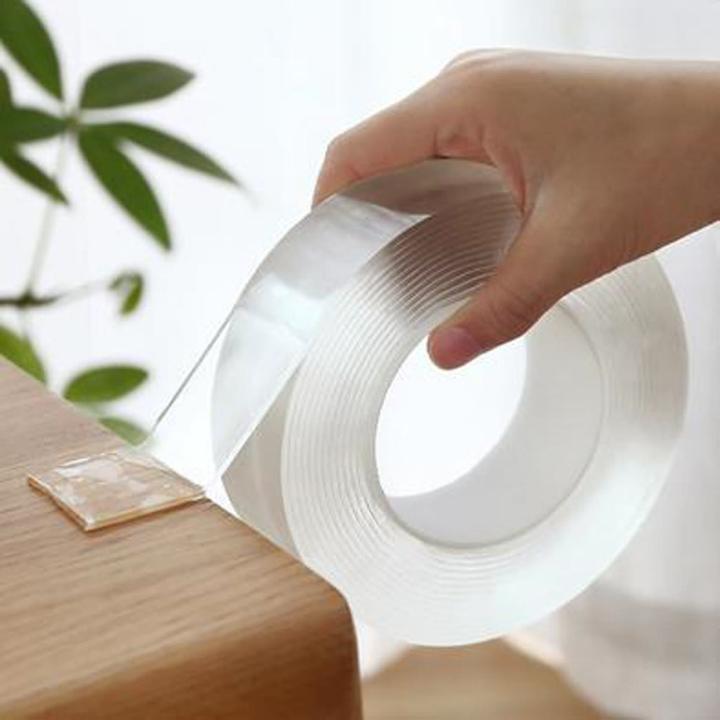 Hand trekt de doorzichtige nano tape van de rol aan de rand van een plank