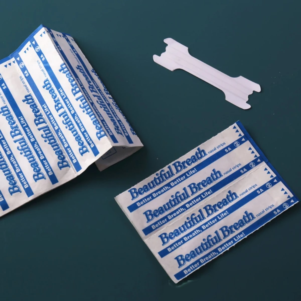 Transparante neusstrip naast de per stuk verpakte zakjes op een donkergroene ondergrond