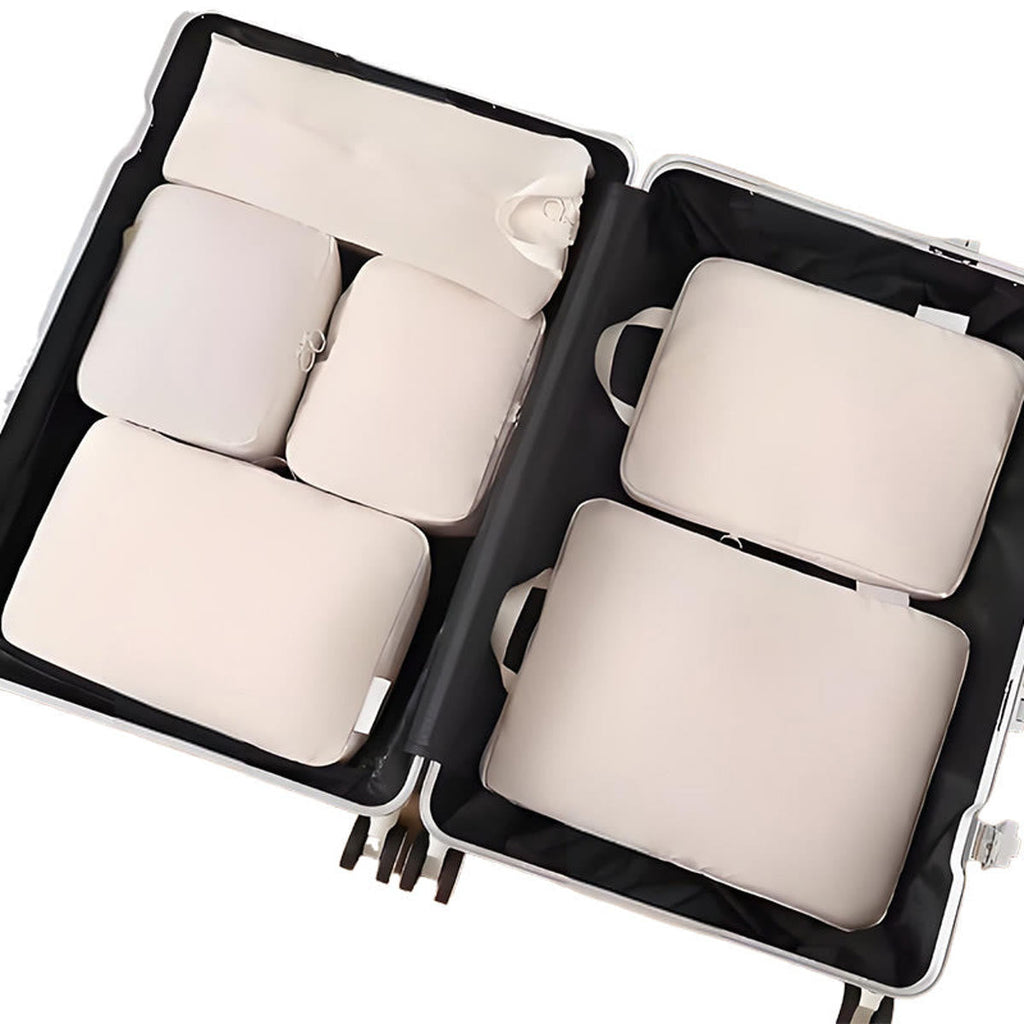 Packing cubes in zand: zes packing cubes plat in een open koffer, van bovenaf gezien