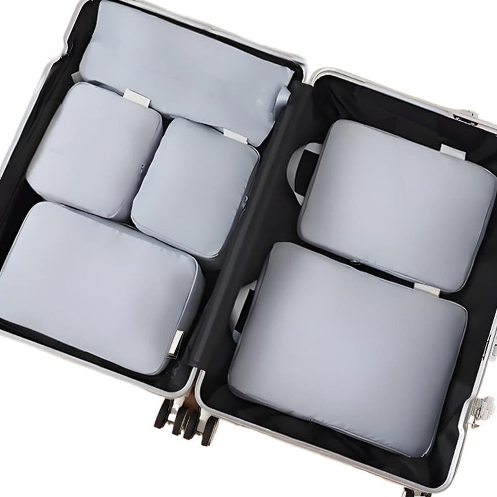 Packing cubes in grijs: zes packing cubes plat in een open koffer, van bovenaf gezien